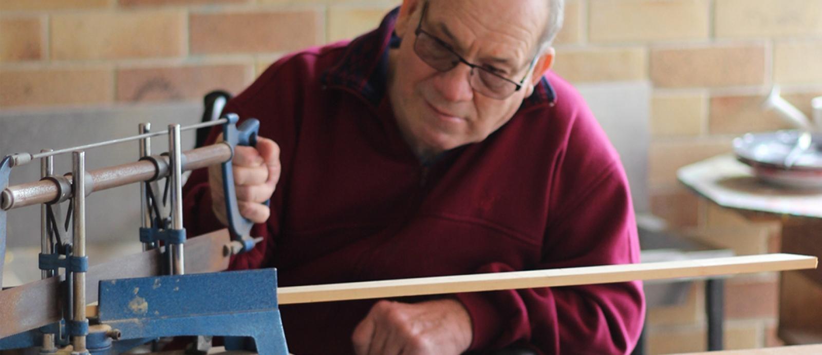 elderly man does woodwork as part of a testimonial about NDIS support coordination