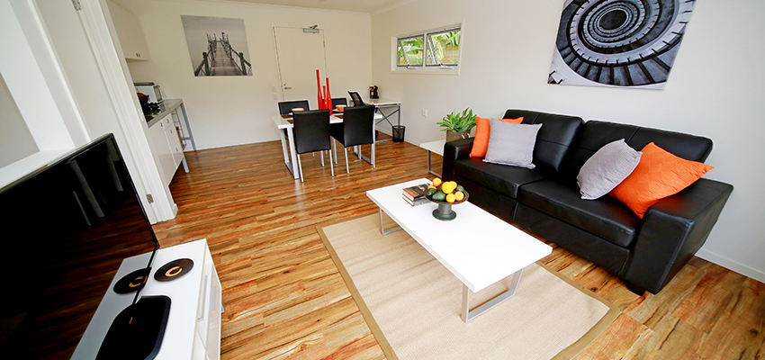 Loungeroom with tv cabinet, dark coloured couch and art hung on the wall