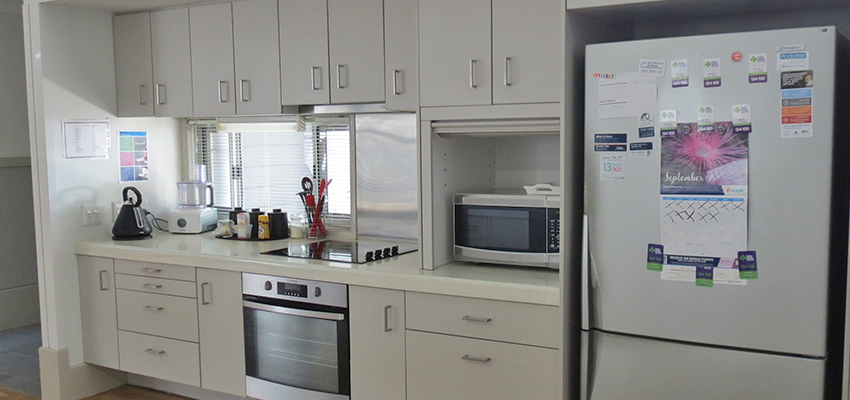 White kitchen cupboards and a stainless steel refrigerator
