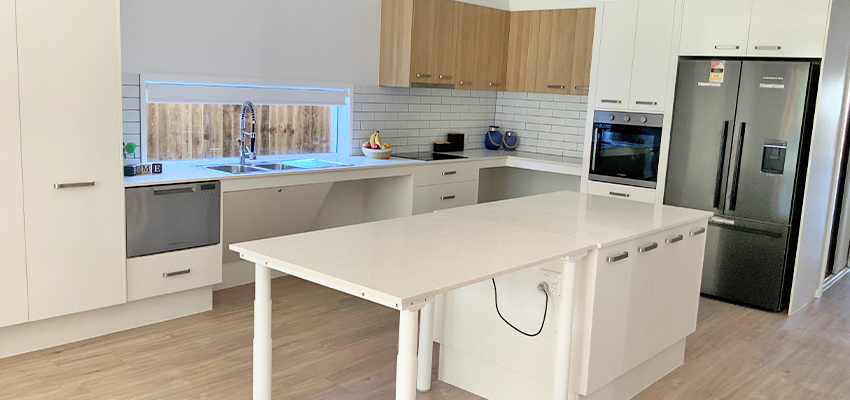 Kitchen with white cabinets and an accessible island bench