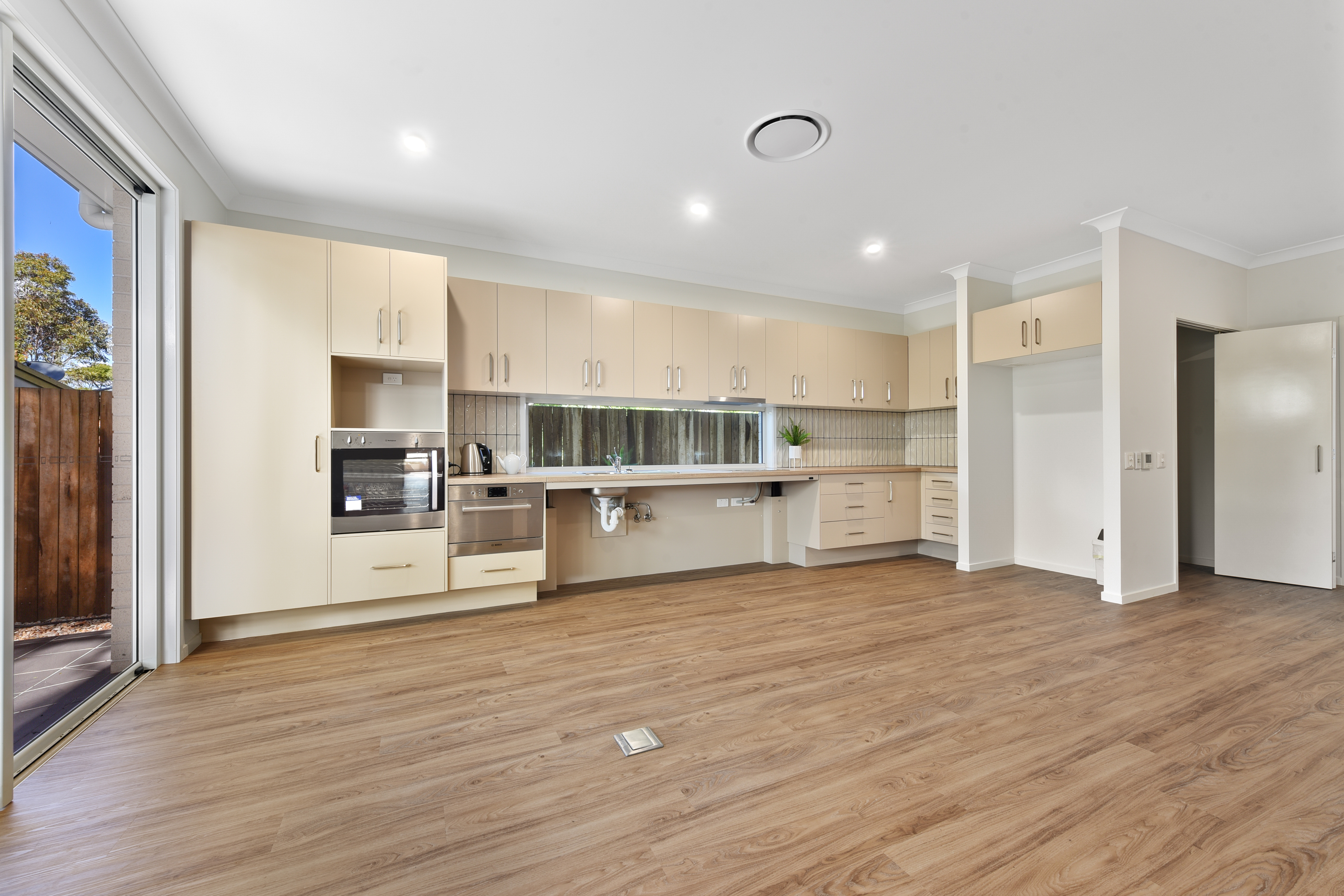 Unfurnished Kitchen and Dining area with wooden floorboards and large opening doors