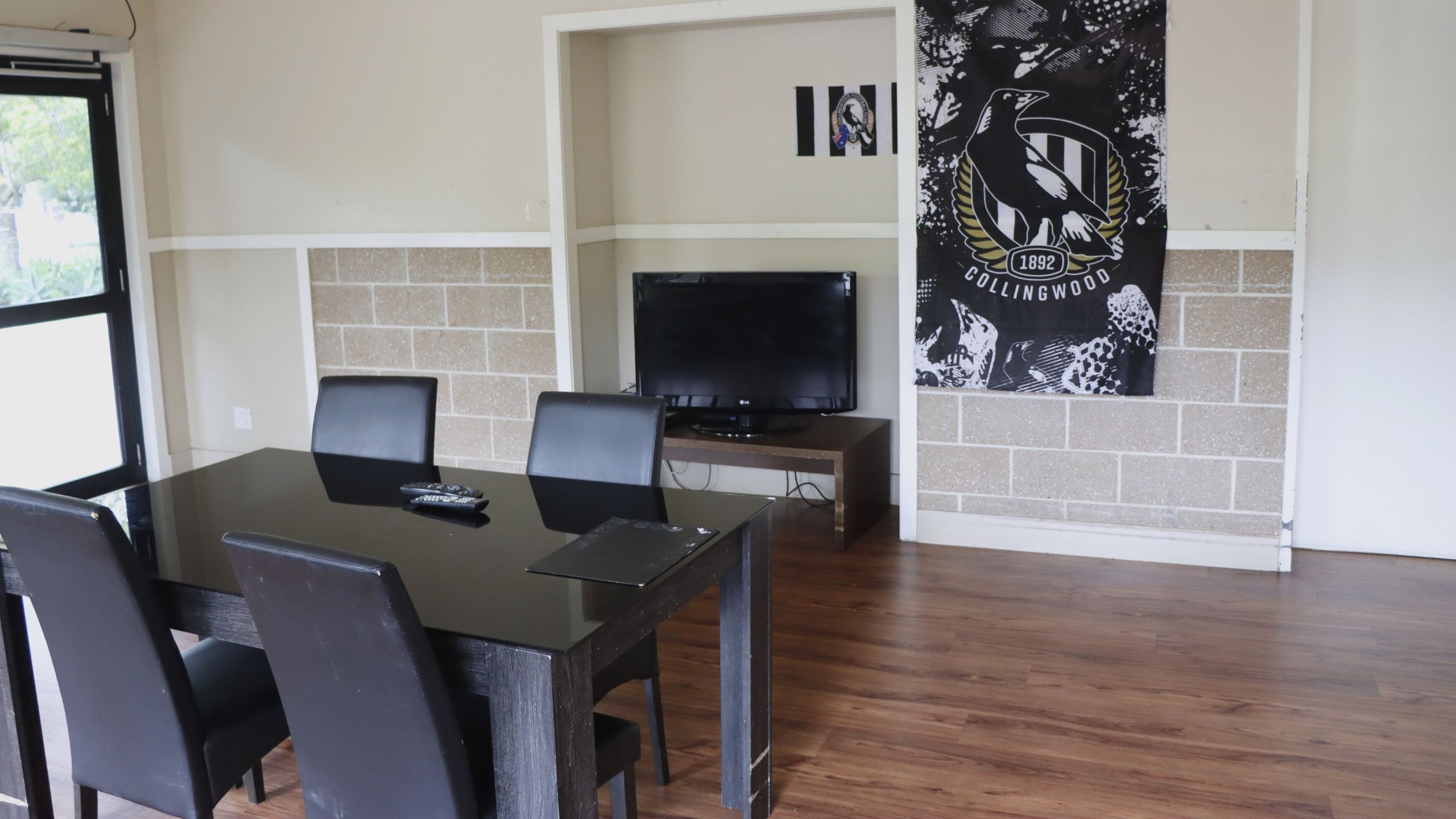 Lounge / dining area with a TV and Collingwood flag in the background
