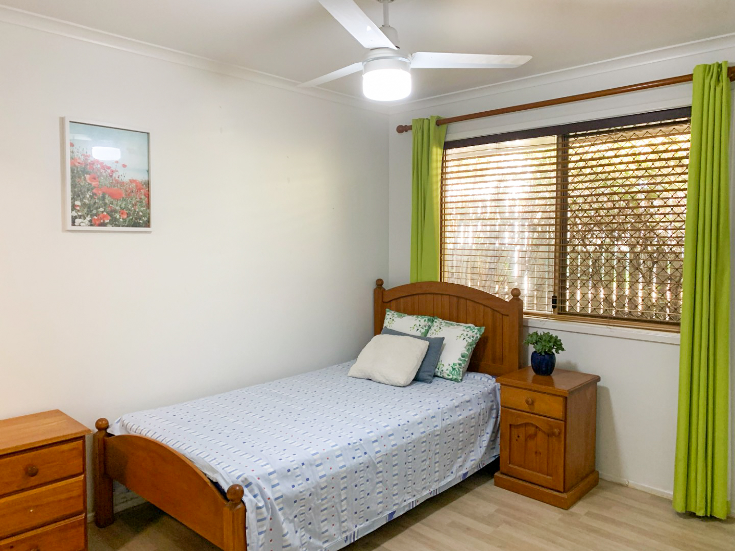 Bedroom with a single bed in , ceiling fan and green curtains