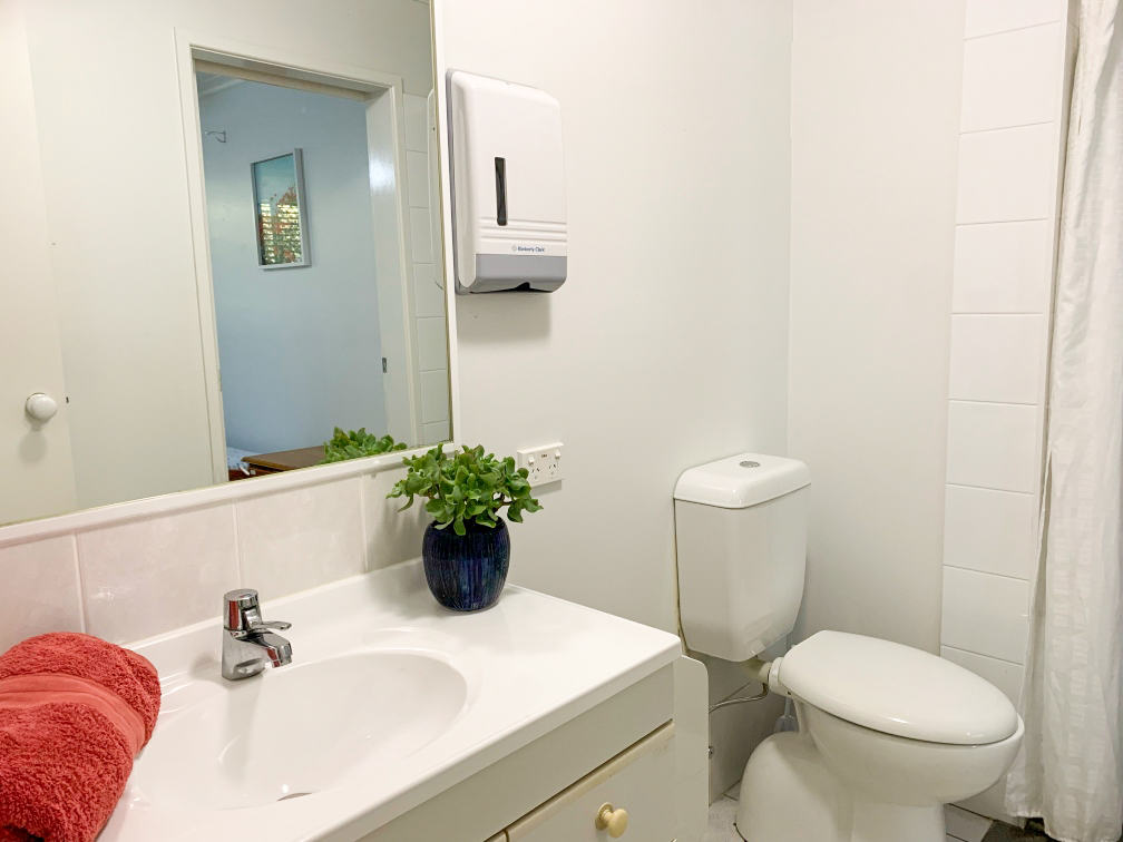 A white bathroom with a toilet, sink and a large mirror