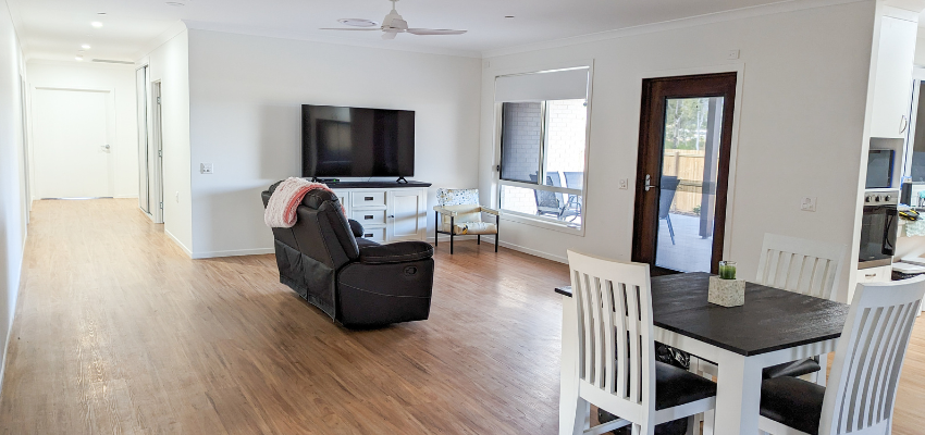 An image of the lounge room, showing a wide hallway to the bedrooms