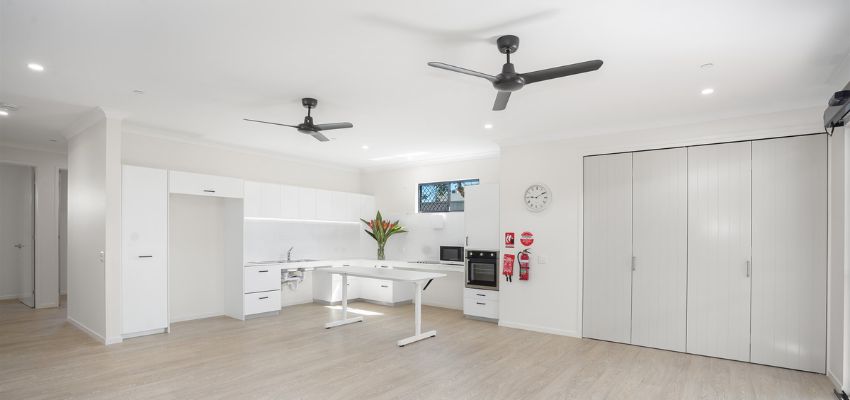 Indoor living area, open plan showing a white kitchen