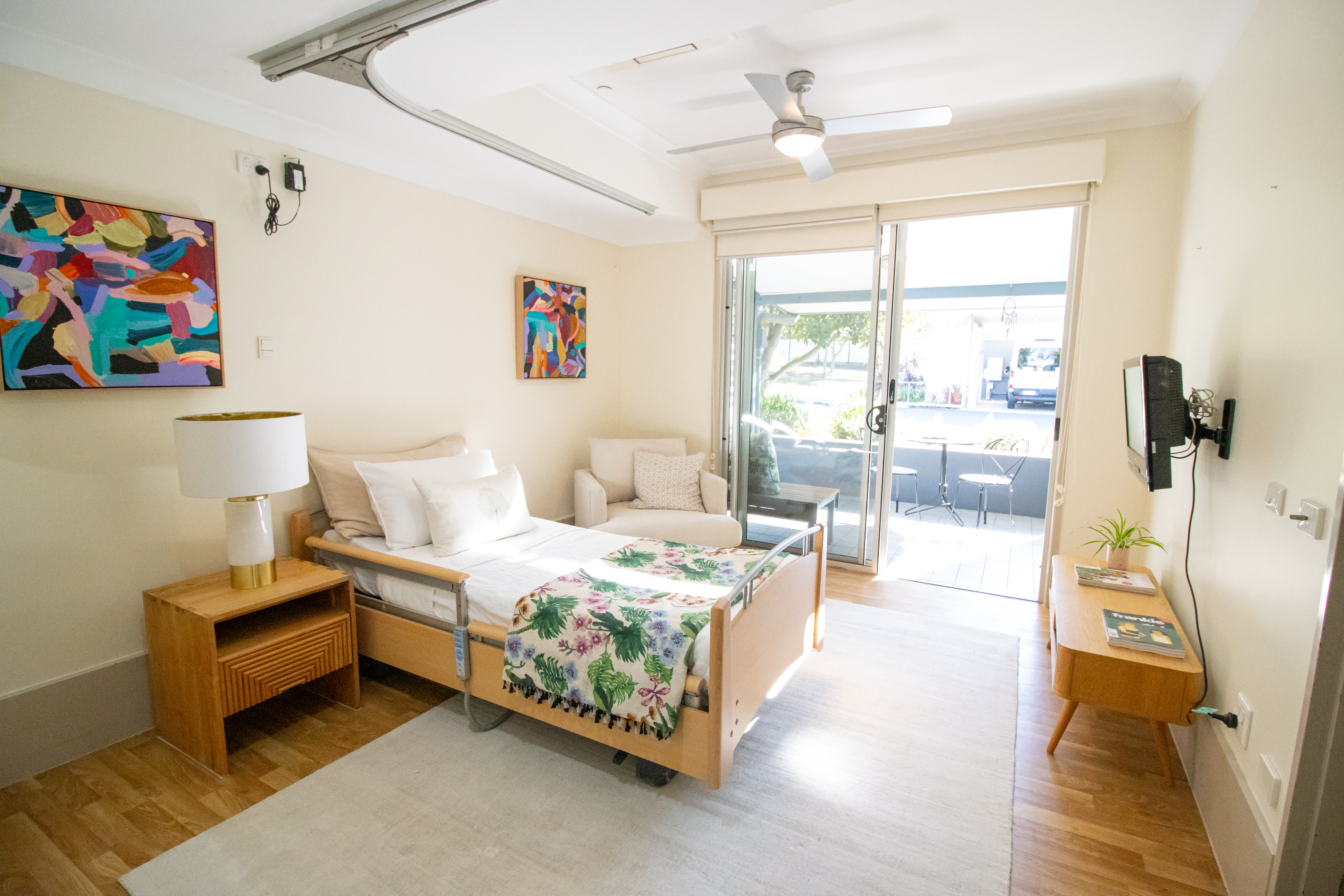 Bedroom with an adjustable bed in front of a TV, and with a ceiling hoist