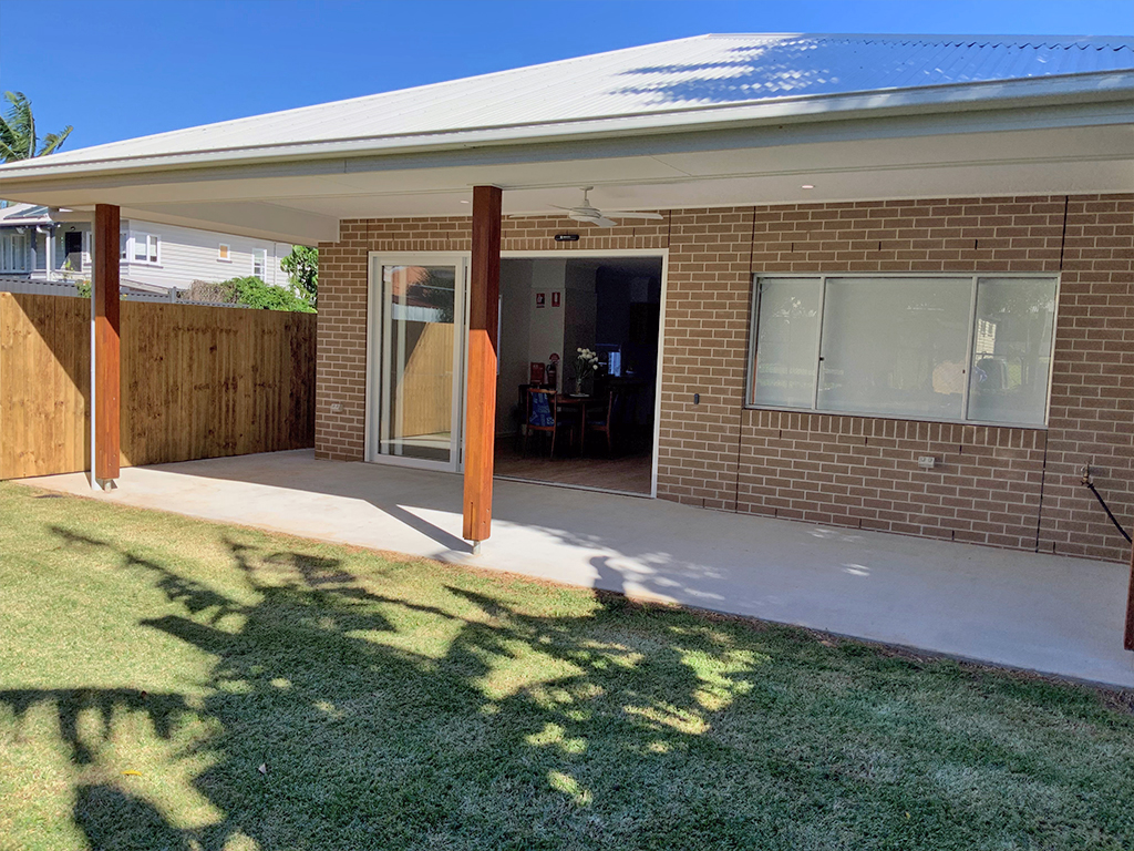 Backyard showing a section of grass and the back of the house with a patio