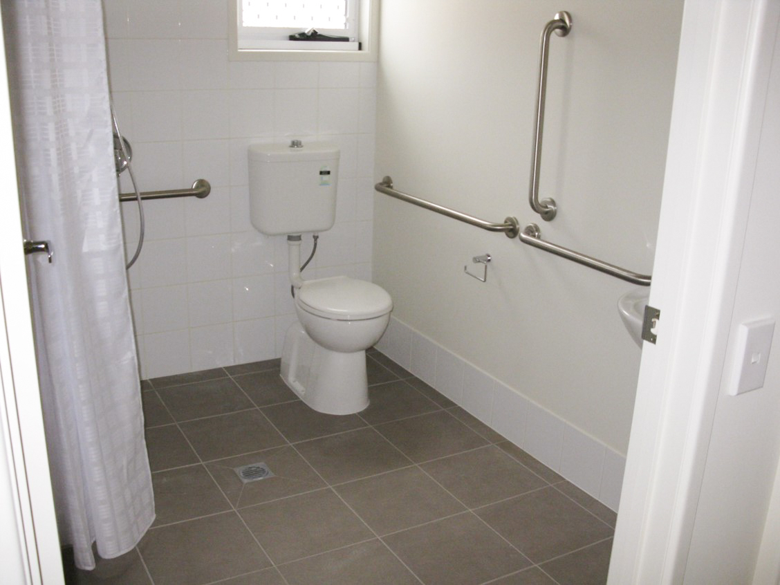A bathroom with accessible rails along the walls