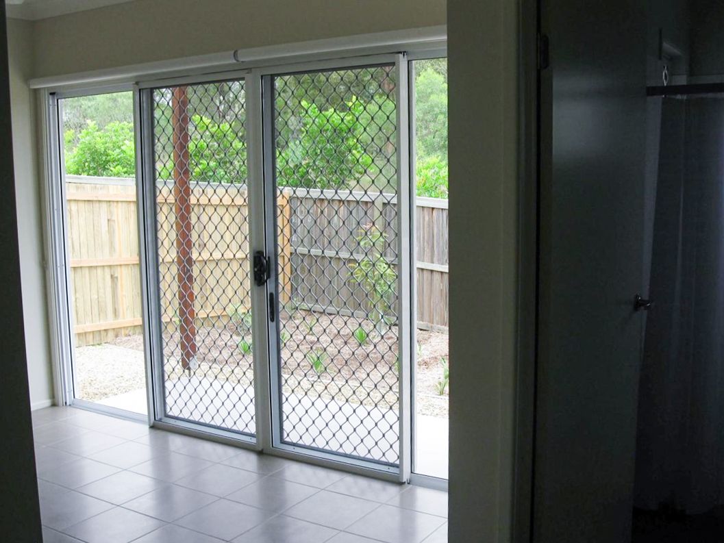 A photo of a lounge room with large glass doors leading to outside