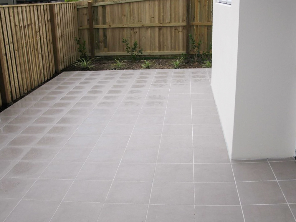 An outdoor patio with grey tiles surrounded by a wooden fence