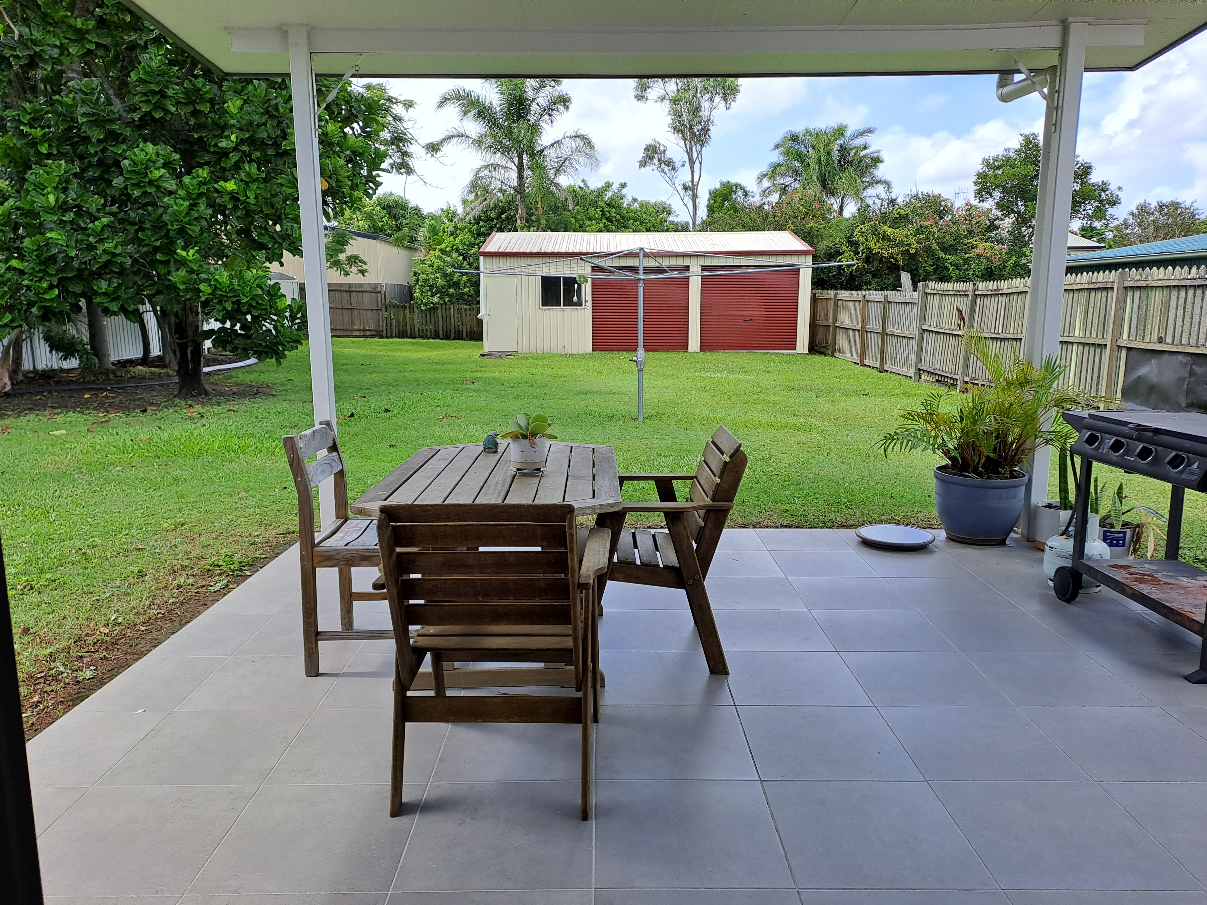 An outdoor dining area with a yard and a shed behind