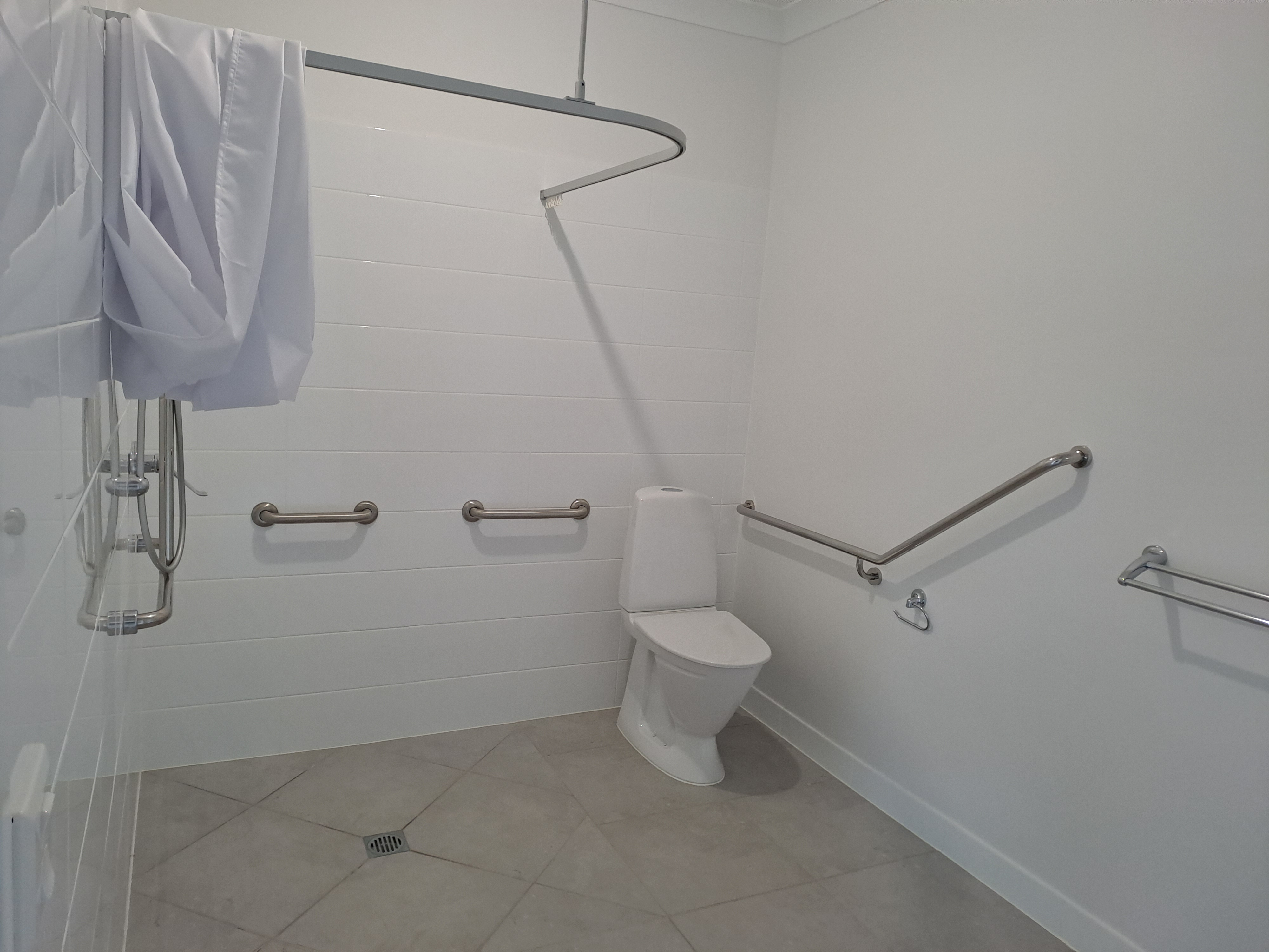 A white bathroom with handrails