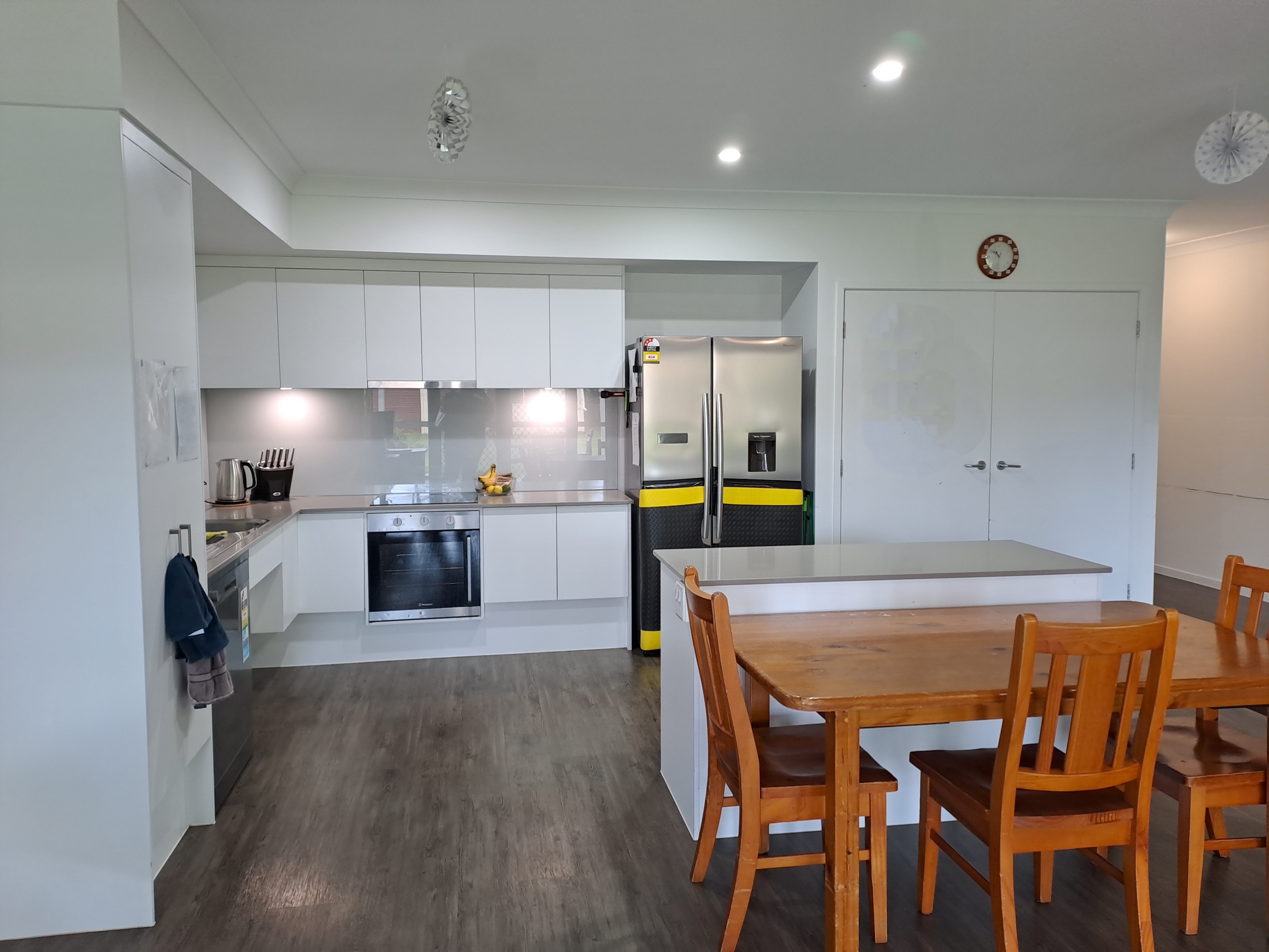 A white kitchen with a wooden dining table and chairs