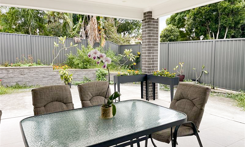 A patio with a table and chairs with a lawn behind it