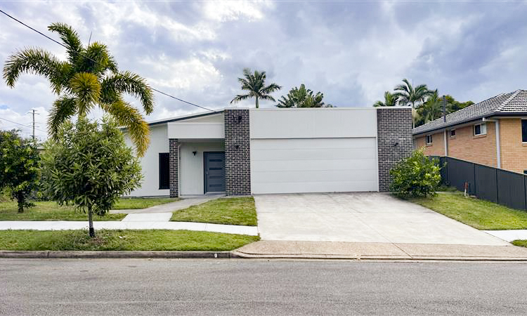 Front of a grey house with a white garage and a front yard