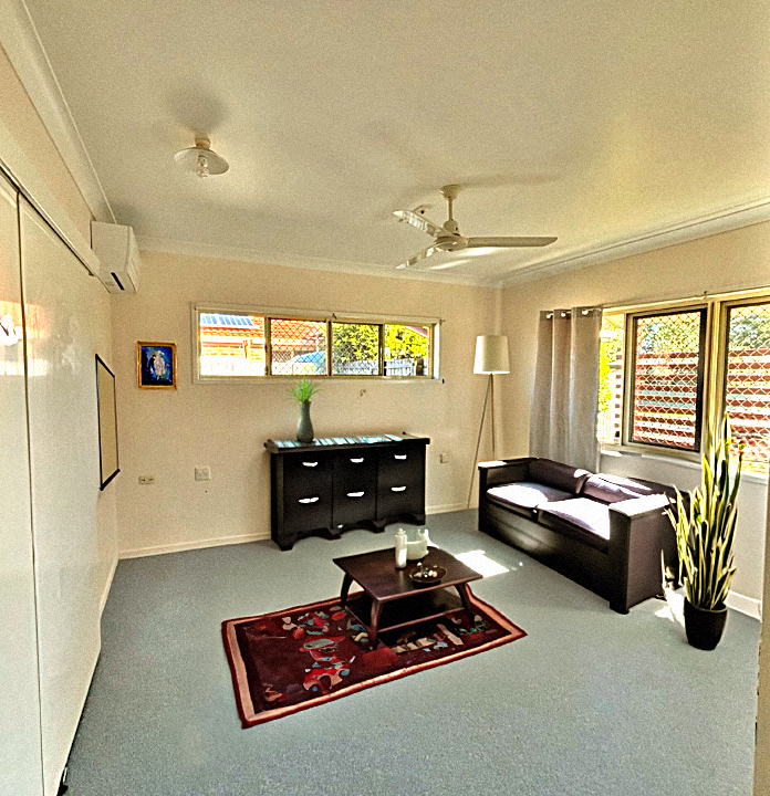 An image of a room with a cupboard visible, a red mat and green carpet