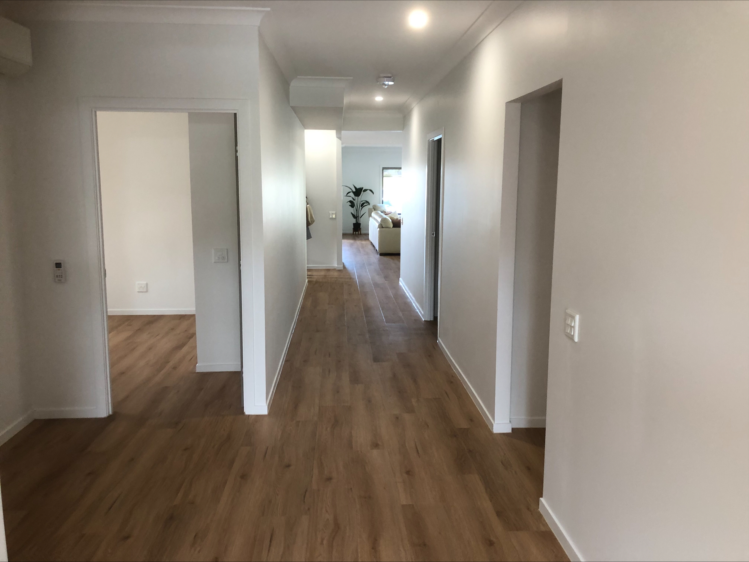 An image showing the hallway, with wooden flooring, white paint on the walls, and modern downlighting.