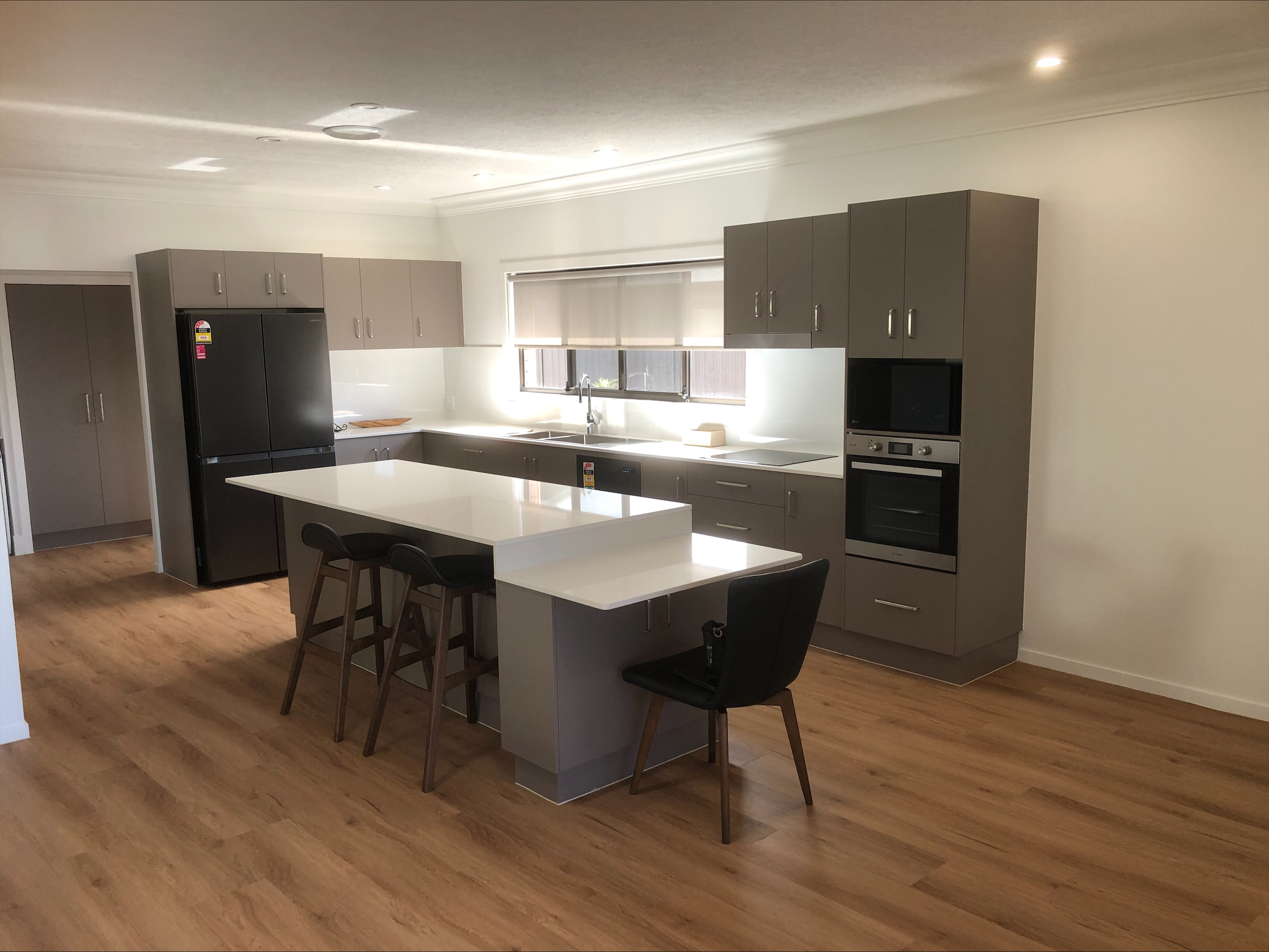 An image showing a modern kitchen, with island benchtop and wooden flooring.