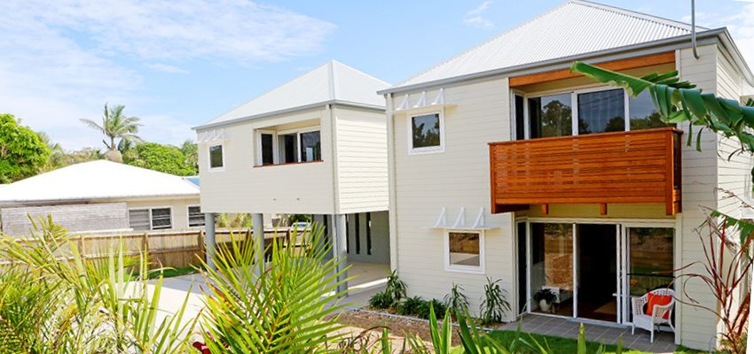 Exterior of two storey house with white paneling and brown deck