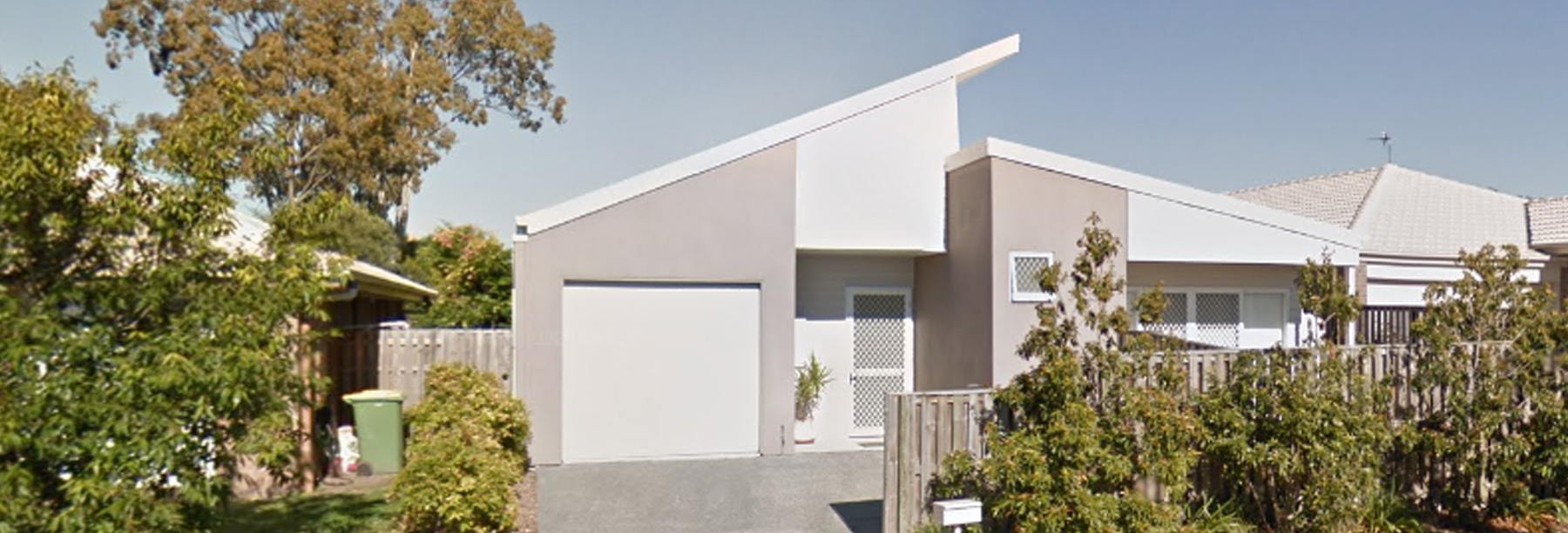 An image showing the front of the property - with green trees and the house visible