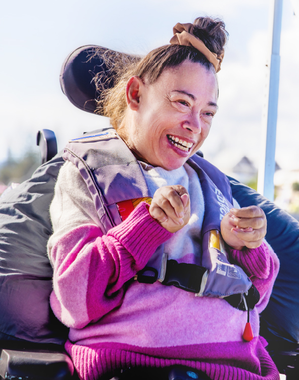 A woman in a wheelchair is on a boat sailing down a river. 
