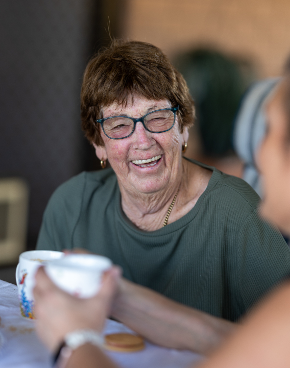 A woman in her home engaging in a lively conversation and having a coffee with another person.