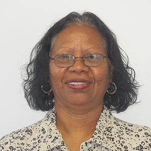 A professional headshot of Fiona. She has short dark hair and is wearing glasses and a patterned blouse.