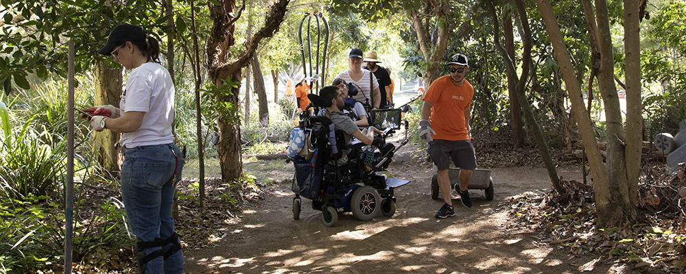 People outside, some standing and some in wheelchairs, working in the garden