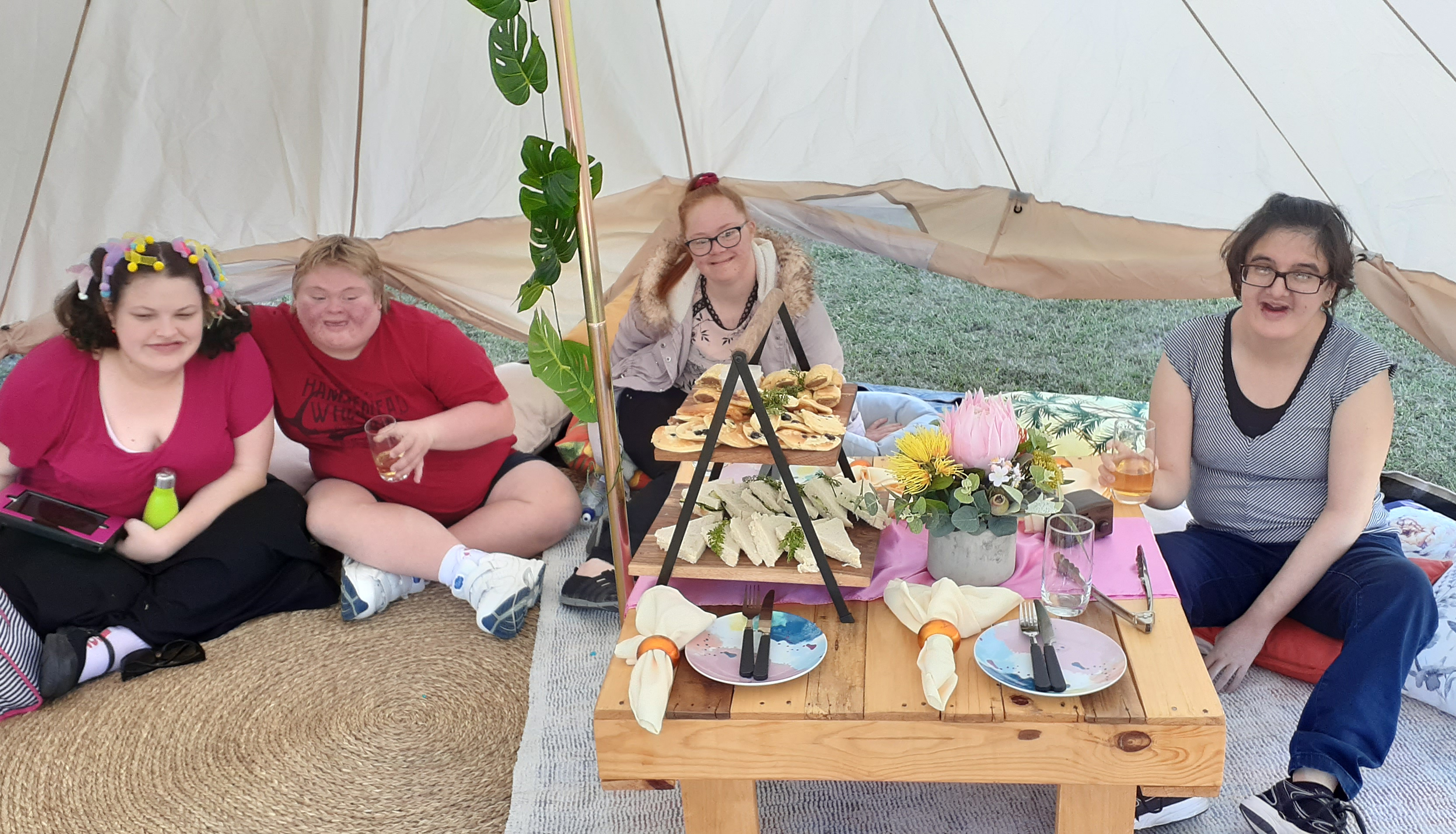 Four women sitting around a low picnic table smiling for a photo