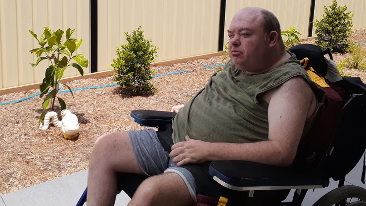 Bradley sitting in teh backyard of his new home in his wheelchair