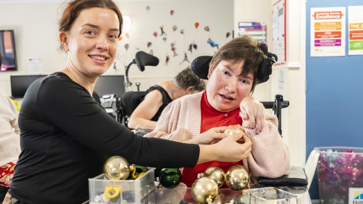 Two ladies sat with Christmas baubles in front of them