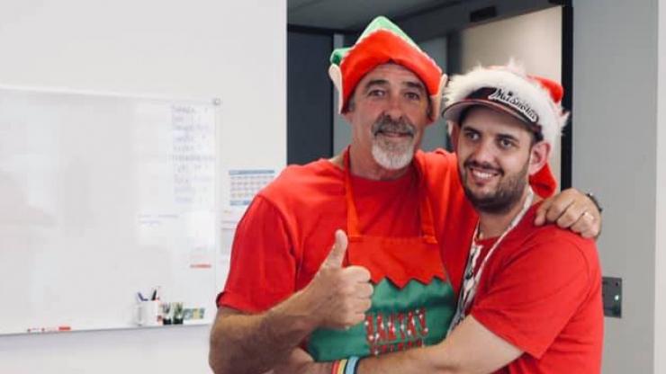 Two people wearing red Christmas shirts and hats