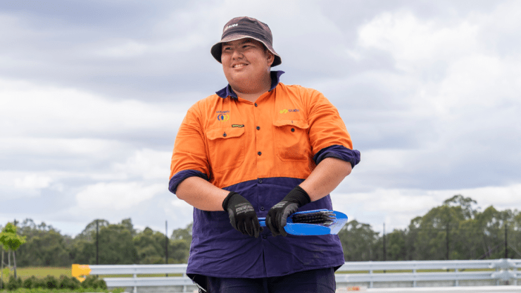 A man stanidng in a car park wearing orange hi vis