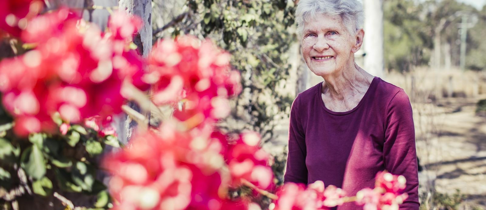 An older woman sitting outside in her garden