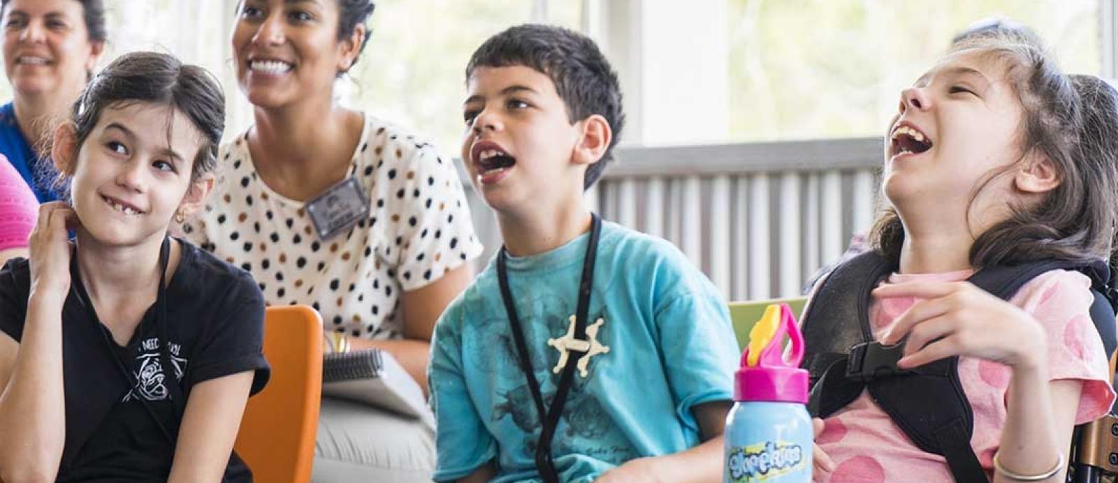 Group of children with disabilities smile and laugh in a group setting